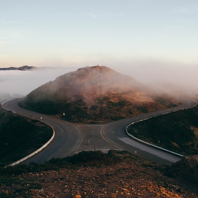 两个人站在山前灰色水泥路上的鸟瞰图